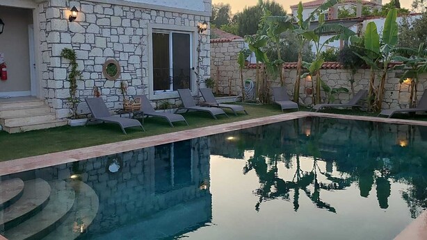 Ein Gebäude aus Stein mit Pool, Sitzgelegenheiten im Freien und einem Garten.