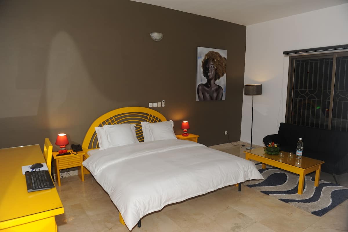 Ein Hotelzimmer mit Bett, Schreibtisch, Stuhl, Lampe und einem Bild an der Wand.