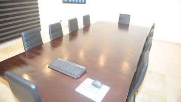 Un salón de conferencias con una amplia mesa de madera, seis sillas, un teclado y un ratón sobre un tapete.