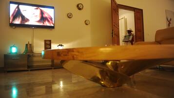 Una sala de estar moderna con una mesa de centro de madera, un televisor de pantalla plana, un reloj y una estatua.