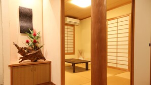 Ein traditioneller japanischer Raum mit Tatami-Boden, einem niedrigen Holztisch und einem Schrank mit einer Dekoration.