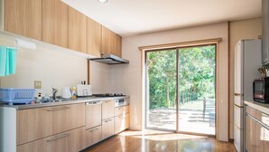 Eine moderne Küche mit Holzausbau, einem eingebauten Ofen und einer großen Schiebeglastür zu einem Außenbereich.