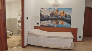 A bedroom with a wooden bed, a large wall-mounted painting of mountains, and a wooden floor. - Hotel Moena (Moena)