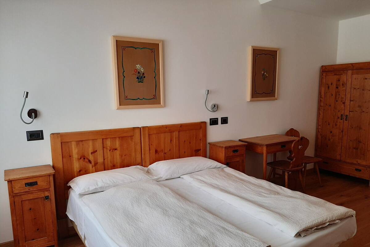 A room with a wooden bed, a wooden desk, a chair, and a wardrobe.