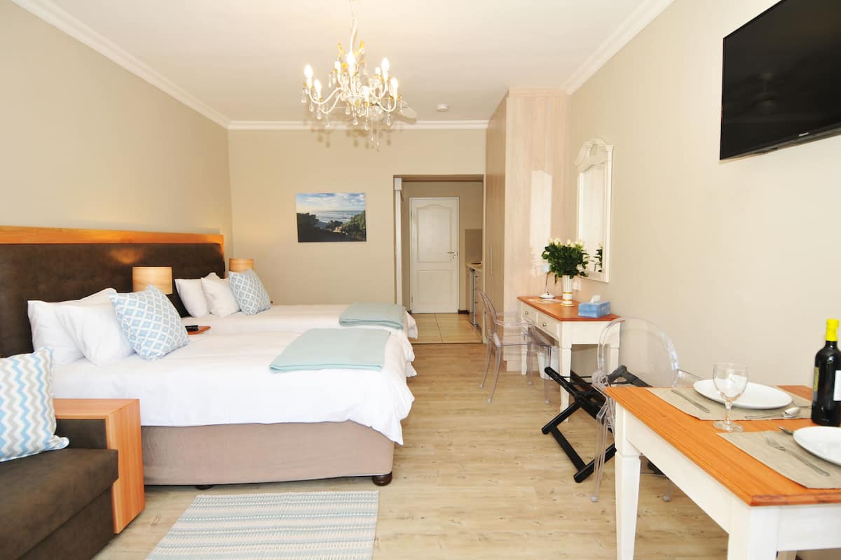 Habitación de hotel con cama, mesitas de noche, escritorio, silla, televisor y candelabro.