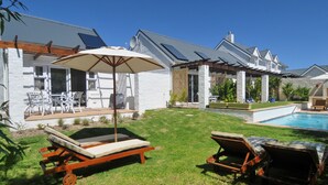 Um quintal com piscina, espreguiçadeiras e um espaço de pátio com mobiliário para áreas externas.