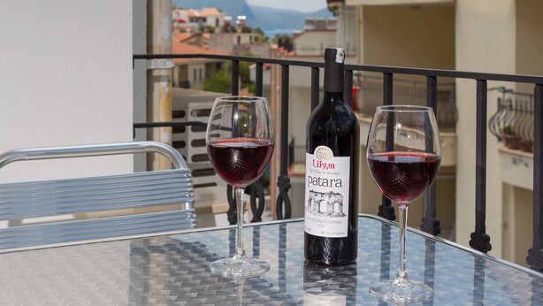 Una mesa con una botella de vino y dos copas en un balcón con vistas a la ciudad.