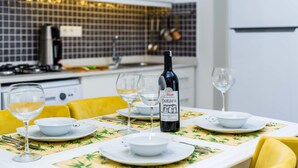 Una mesa de comedor preparada con cuencos blancos, copas de vino y una botella de vino.