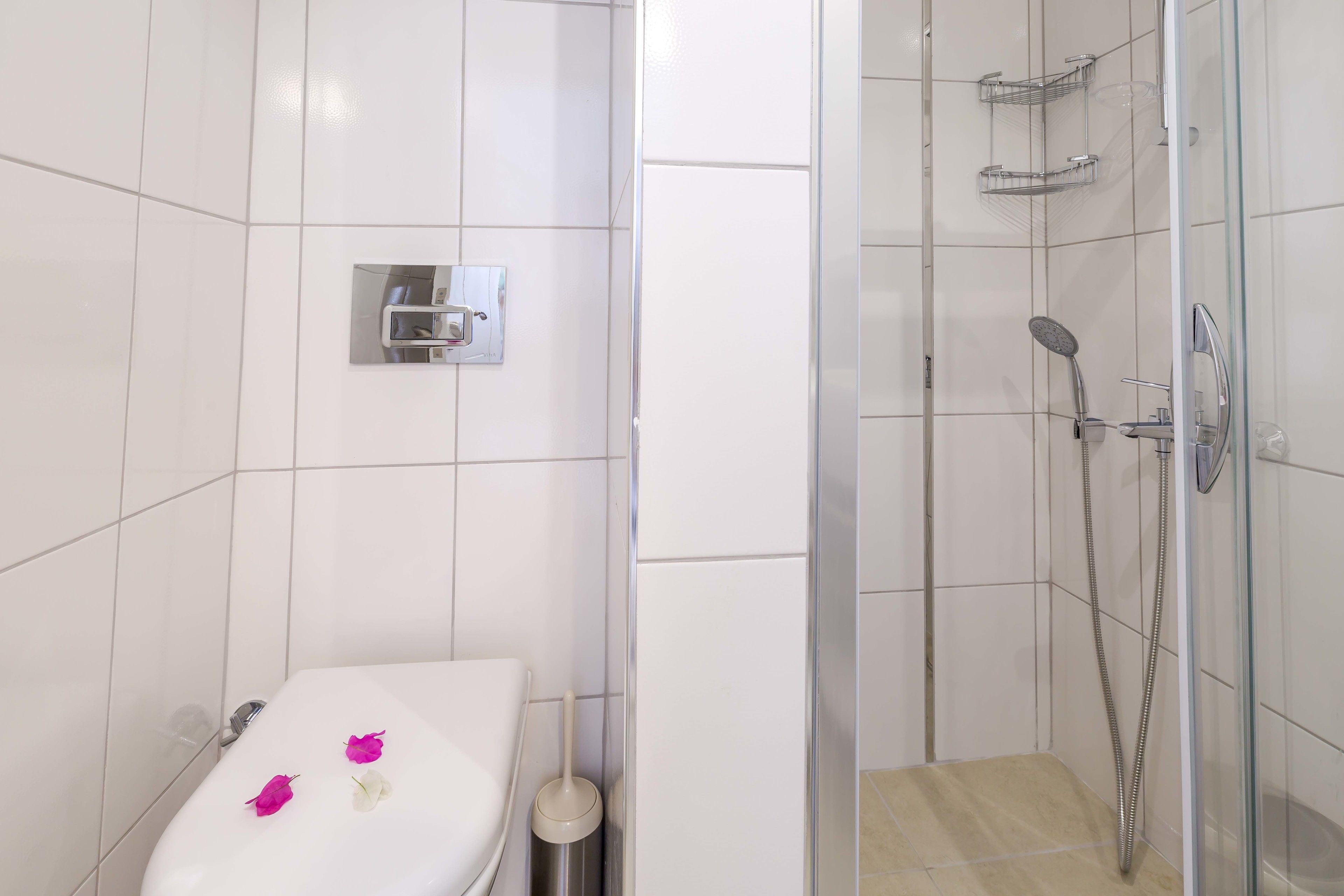 Een badkamer met een wit toilet, een douchecabine van glas en een toiletrolhouder.