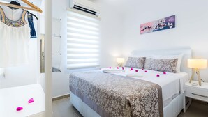 Un dormitorio con cama, mesitas de noche, un perchero y una ventana con persianas.