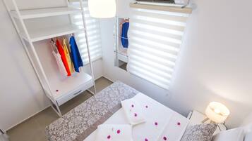 A bedroom with a bed, a bedside table with a lamp, a wardrobe, and a window with blinds.