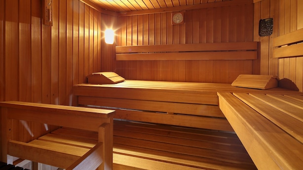 A sauna with wooden benches and a sloped ceiling. - Gästehaus Renate (Laengenfeld)