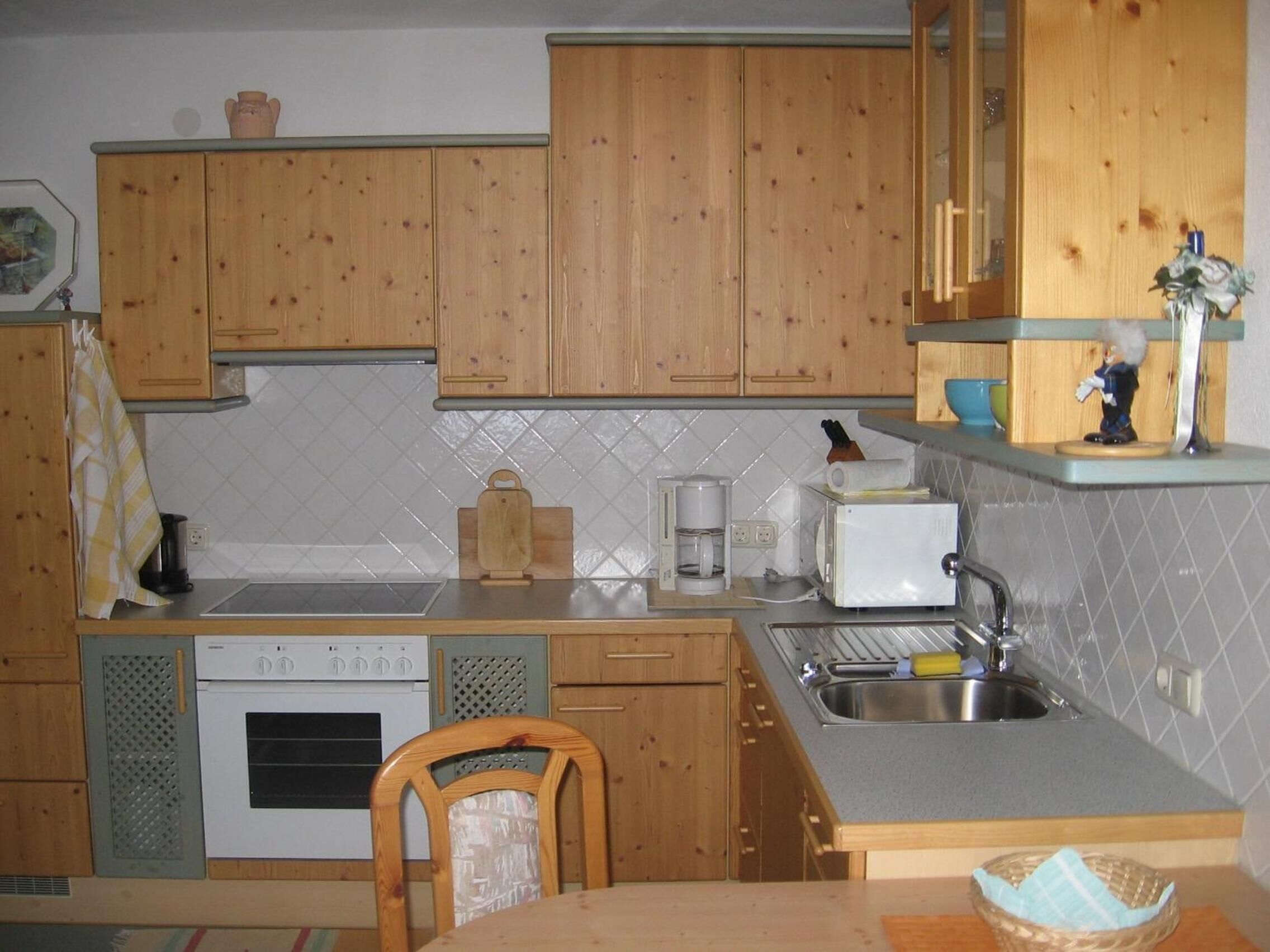 A kitchen with wooden cabinets, a built-in oven, a coffee maker, and a sink.