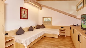 A cozy room with a wooden bench bed, a small table, and a television. - Gästehaus Renate (Laengenfeld)