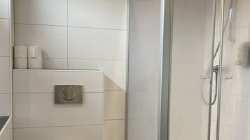 Un bagno moderno con un WC, uno spazio doccia e un portasciugamani per la carta igienica.