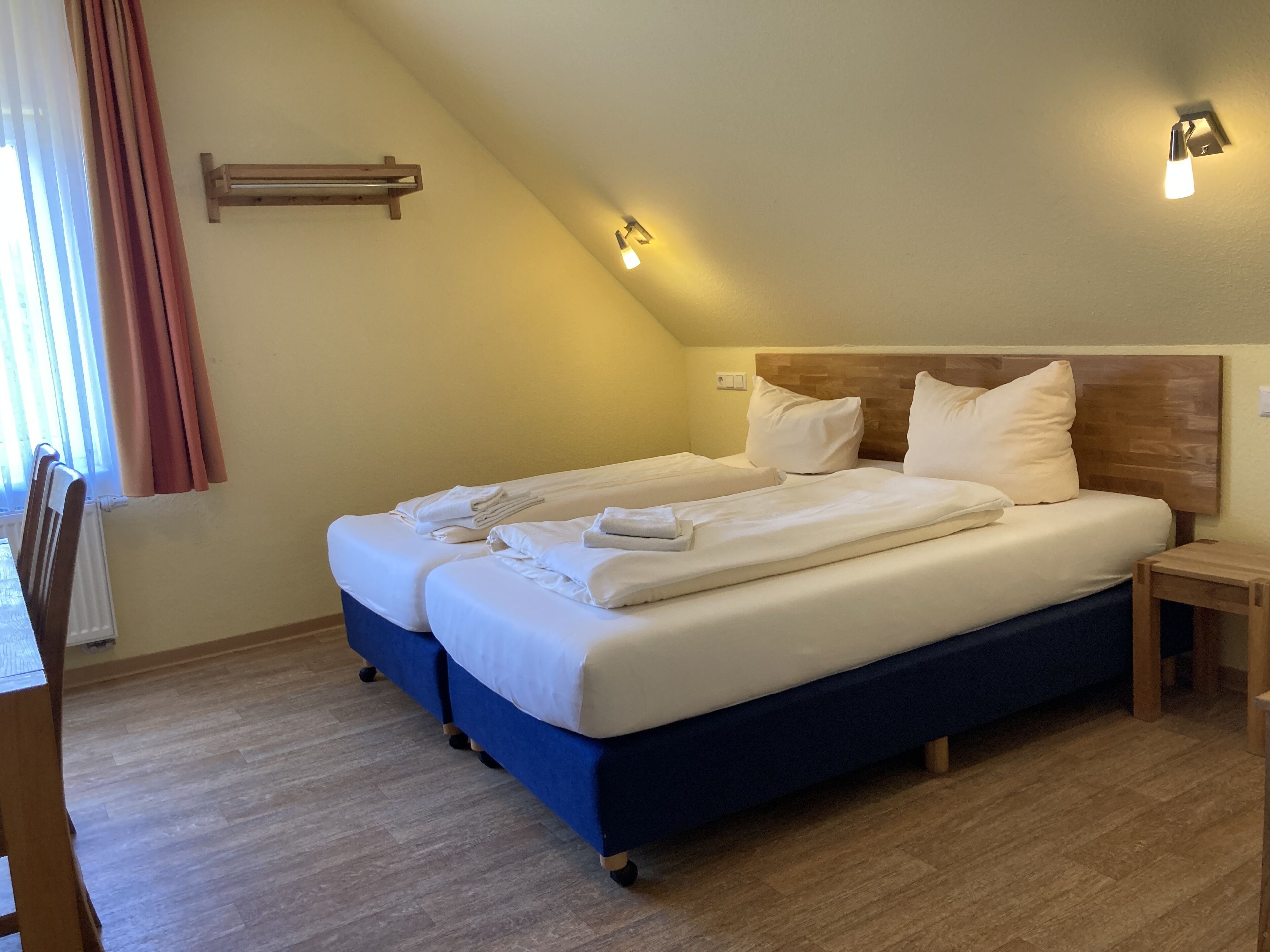 Una cama doble con ropa blanca, un cabecero de madera y una mesita de noche.