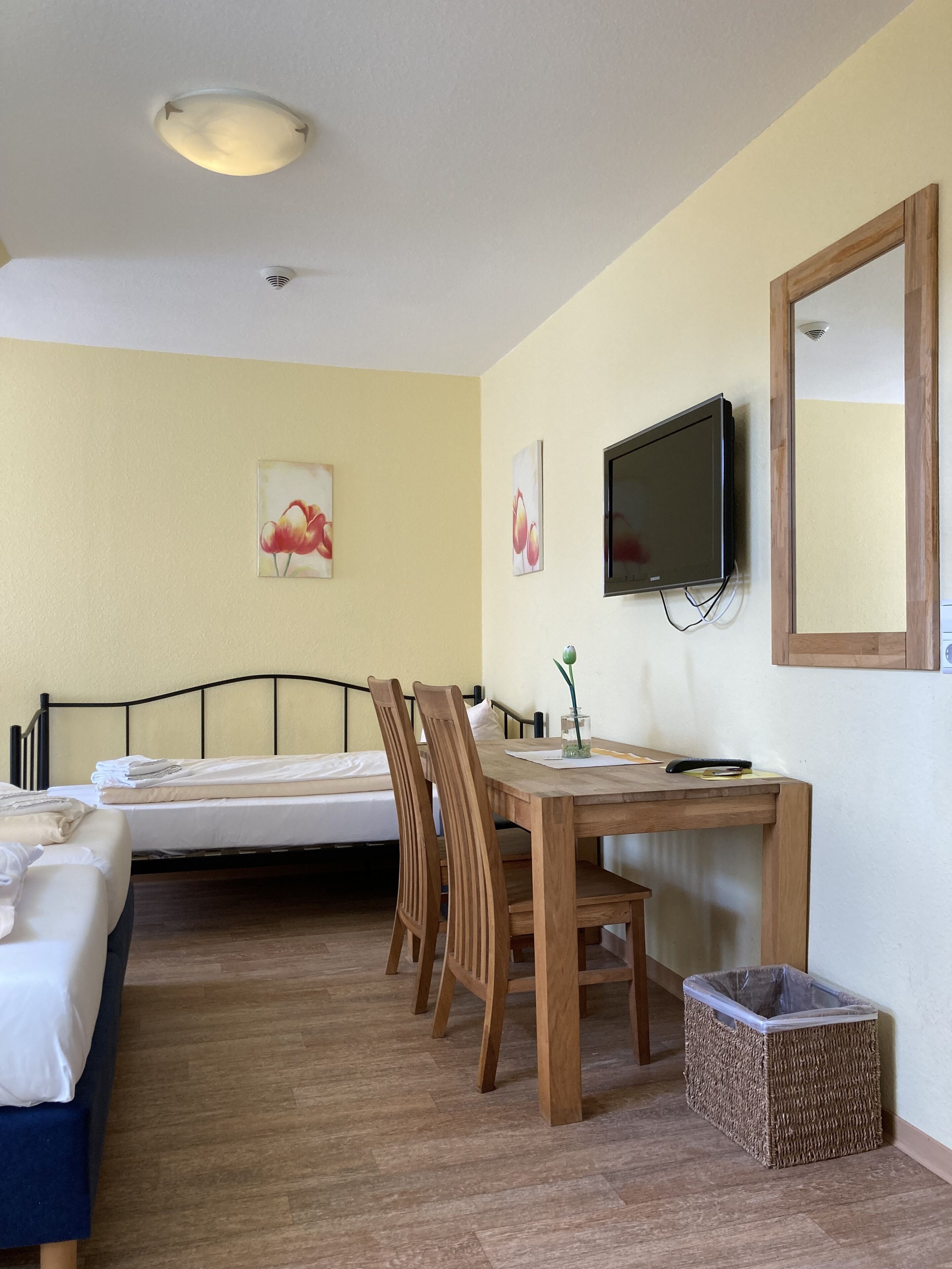 Habitación de hotel con cama, escritorio con silla, televisión y cuadros en la pared.