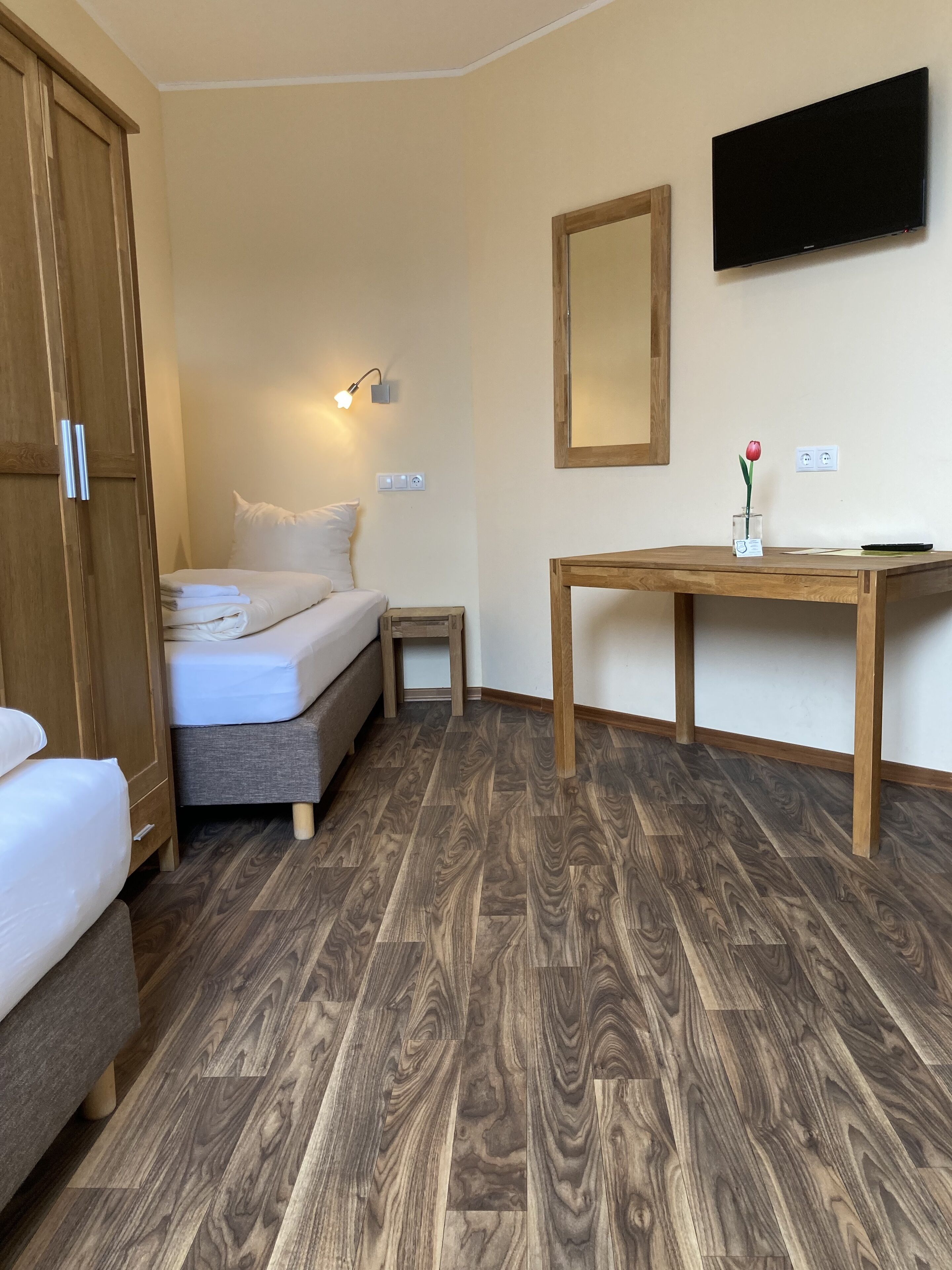 A bedroom with a bed, bedside table, and a wooden wardrobe.