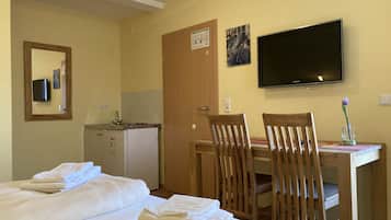 A hotel room with two beds, a desk with a chair, a television, and a door with a sign.