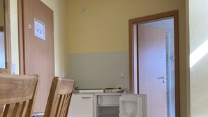 A compact kitchen with a refrigerator, a wooden dining table, and chairs. - Landhotel Vosse-Schepers (Rhede)