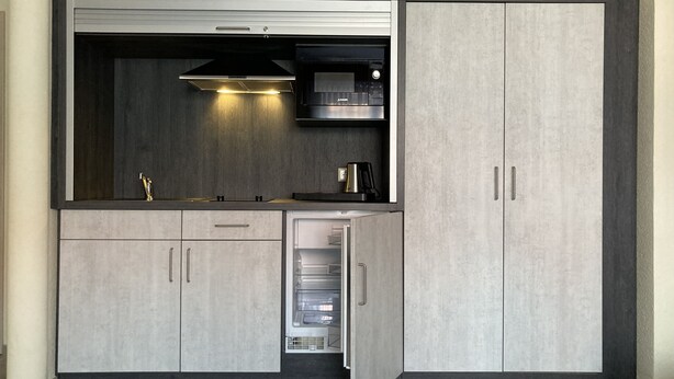 A compact kitchen with a built-in stove, microwave, and a coffee maker. - Landhotel Vosse-Schepers (Rhede)