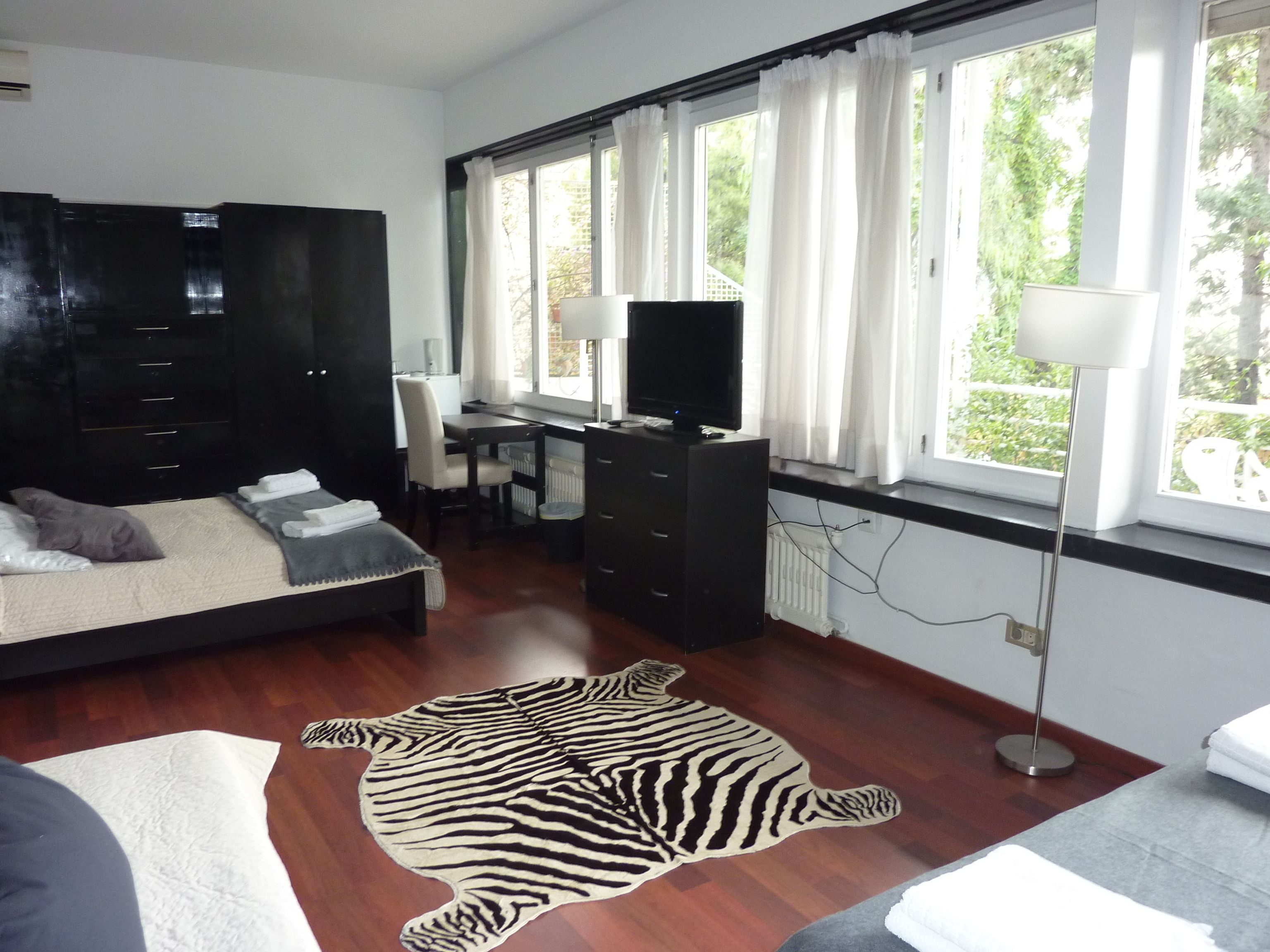 Un dormitorio con una cama, un escritorio, un televisor y una alfombra con estampado de cebra.