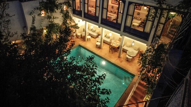 Ein zweistöckiges Gebäude mit Swimmingpool und Außenbereich zum Sitzen.