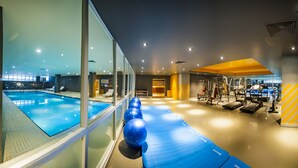 Piscina interior con equipamiento de ejercicio y vestuario.