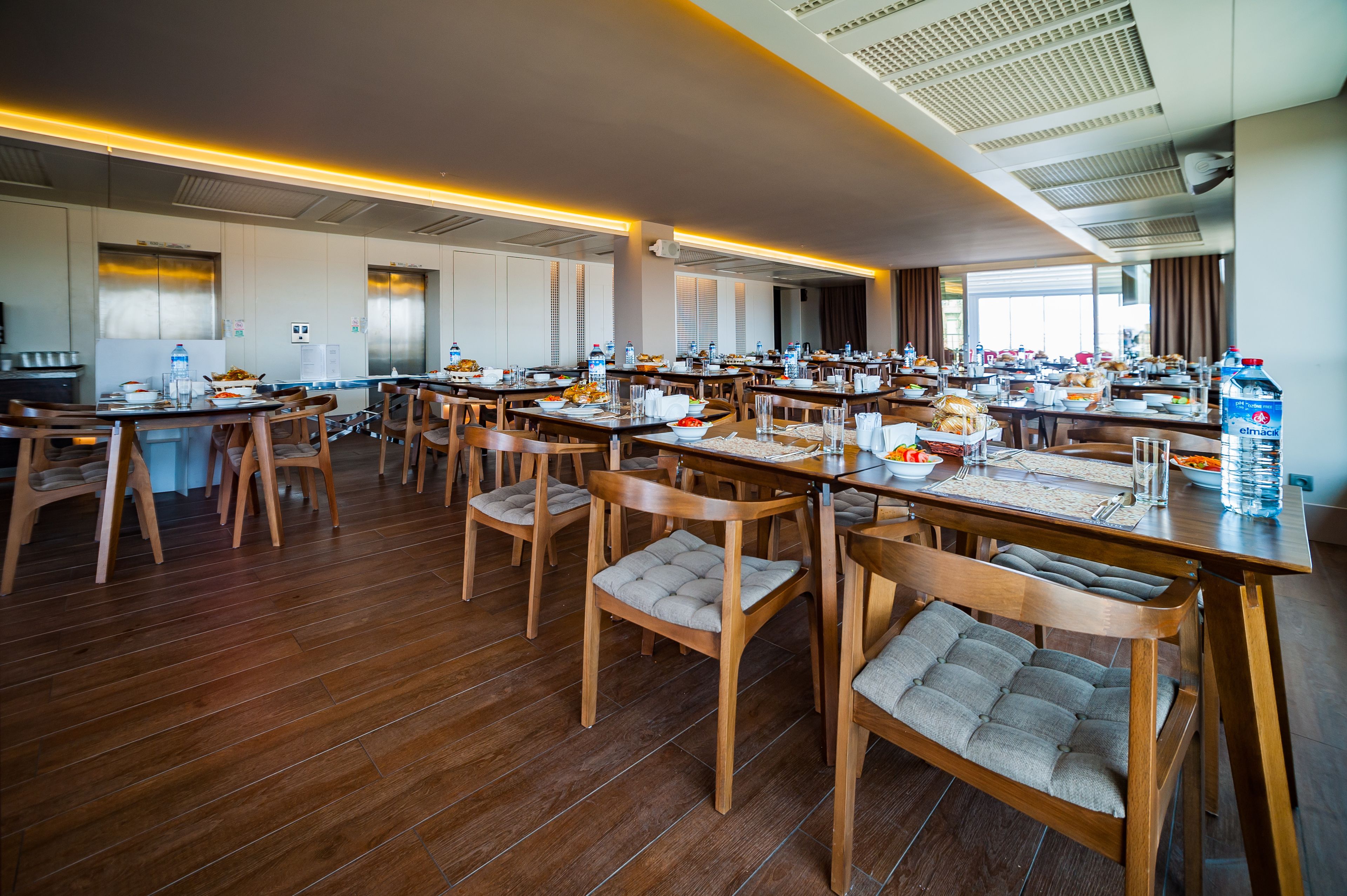 A spacious dining area with multiple tables and chairs, equipped with water bottles and breakfast items.
