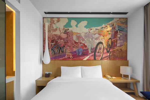 A hotel room with a large bed, a wooden headboard, a nightstand with a lamp, a telephone, and a colorful abstract painting on the wall. - MiniMax Hotel Shanghai Songjiang (Shanghai)