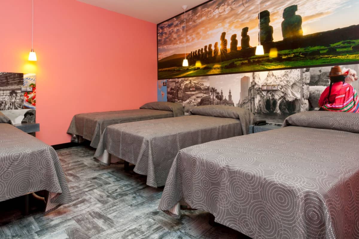 A hotel room with four single beds, a large mural on the wall, and a hanging light fixture.