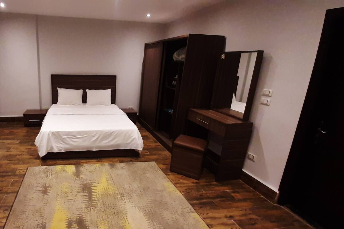 Quarto de hotel com cama, sofá, escrivaninha e armário.