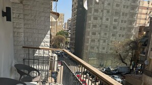 A balcony with a stone wall, metal railing, and wicker furniture. - Nakhil Residence (Giza)
