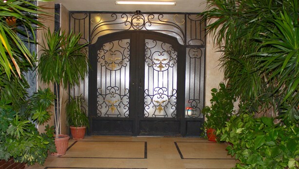 A gated entrance with decorative ironwork, potted plants, and a tiled floor. - Nakhil Residence (Giza)