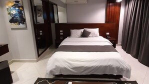 A hotel room with a large bed, a desk with a chair, a mirror, and an air conditioning unit. - Nakhil Residence (Giza)