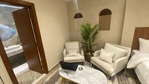 A modern hotel room with a bed, two sofas, a coffee table, a laptop, and a potted plant. - Nakhil Residence (Giza)
