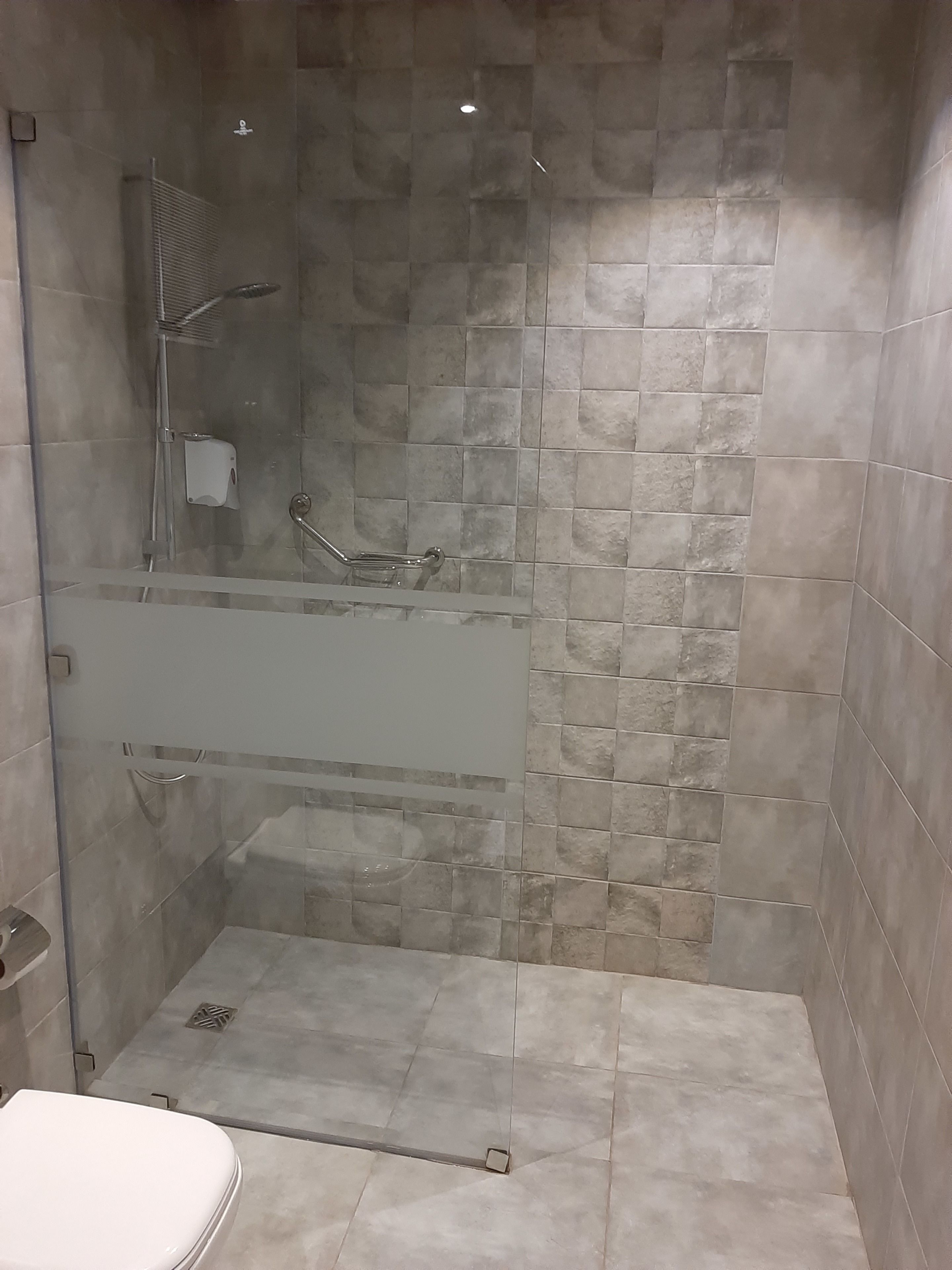 Ein modernes Badezimmer mit einer Glasdusche, einer Toilette und einem Waschbecken.