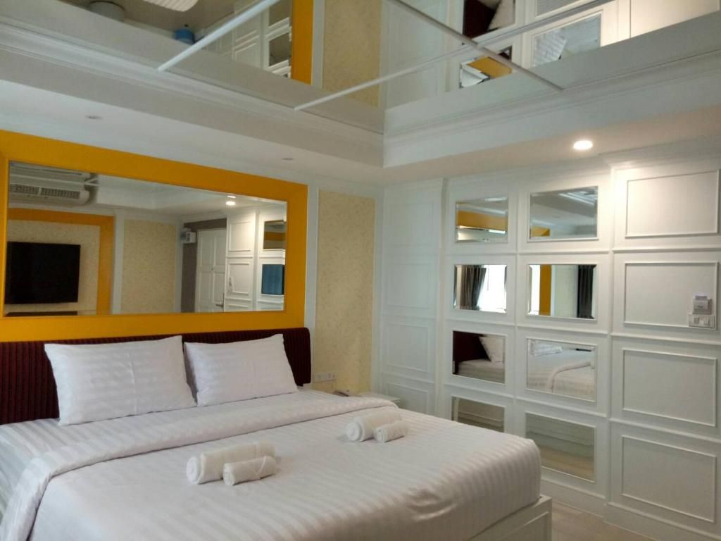 A hotel room with a large bed, a mirror, and built-in shelving.