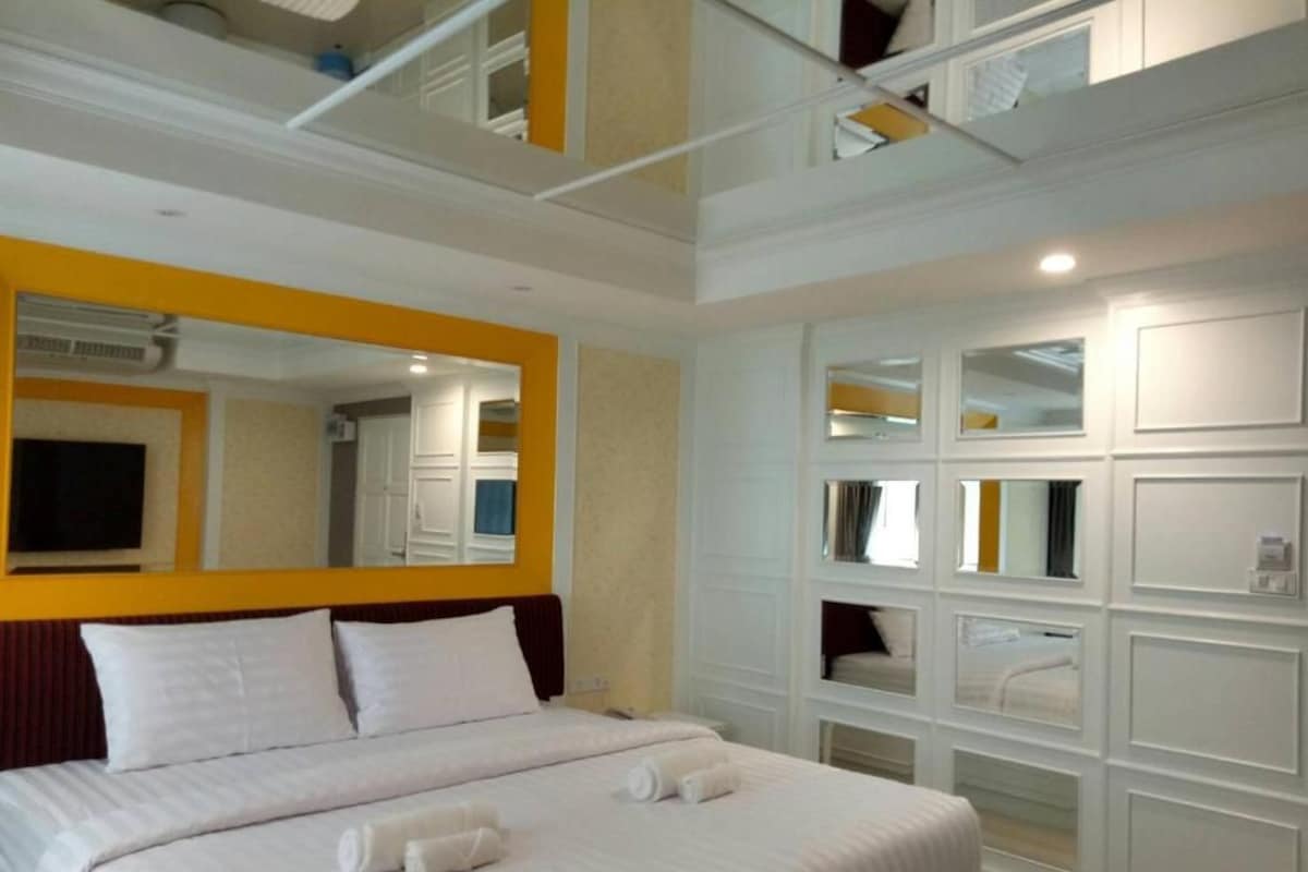 A hotel room with a large bed, a mirror, and built-in shelving.
