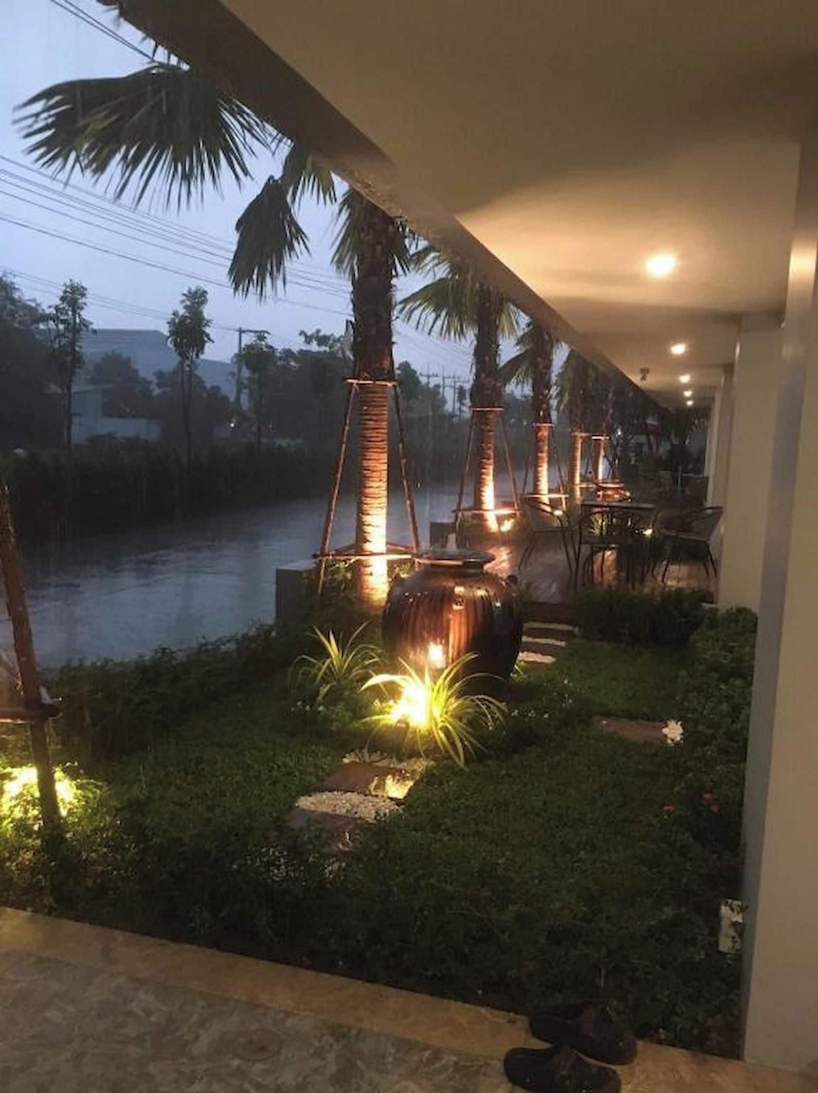 A garden area with palm trees, a water body, and outdoor seating.