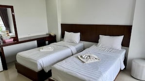 Ein Hotelzimmer mit zwei Betten, einem hölzernen Kopfteil, einem Nachttisch und einem Spiegel.