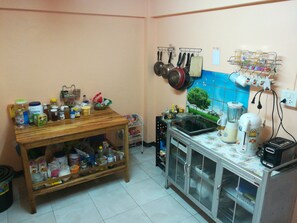 Una cocina con una mesa de madera, un armario de vidrio y diferentes utensilios y electrodomésticos.