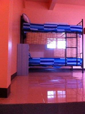 Dormitorio con literas, ventana, radiador y suelo de baldosas.