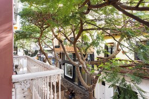 A balcony with a white balustrade overlooking a street with buildings and a tree with green foliage. - Pensión Casablanca (Santa Cruz de Tenerife)