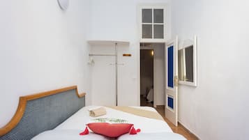 A bedroom with a bed, a window, a door, and a small closet.