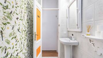 Een badkamer met een wit wastafel, een spiegel en een deur met een bloemen behangpatroon.