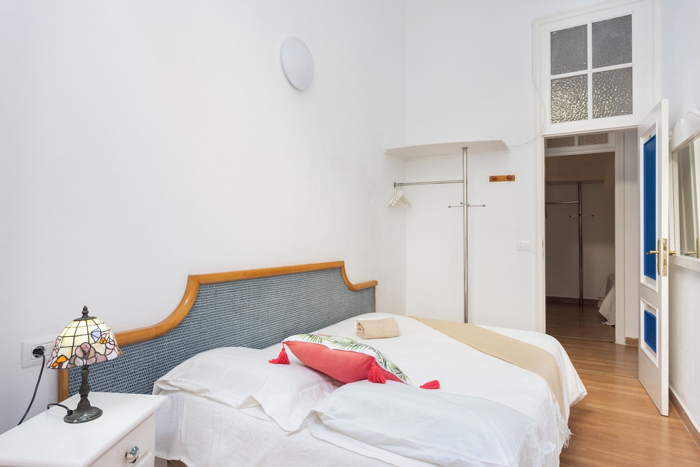 A bedroom with a bed, bedside table, lamp, and a wardrobe.