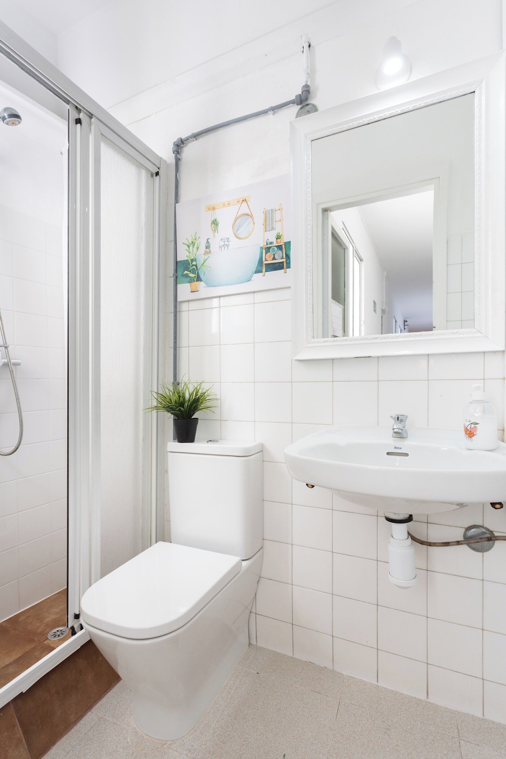 A bathroom with a toilet, sink, shower, and a small potted plant.