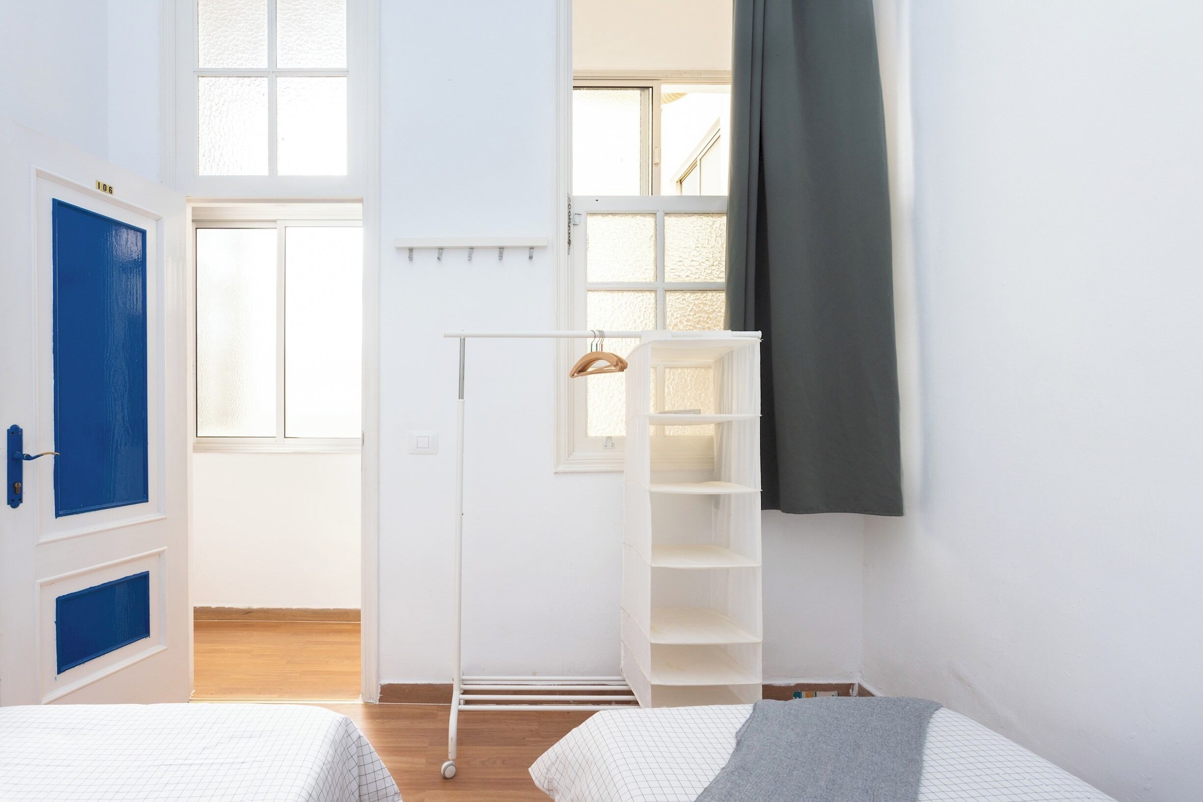 Habitación con dos camas, un armario, un tendedero y una ventana con cortinas.