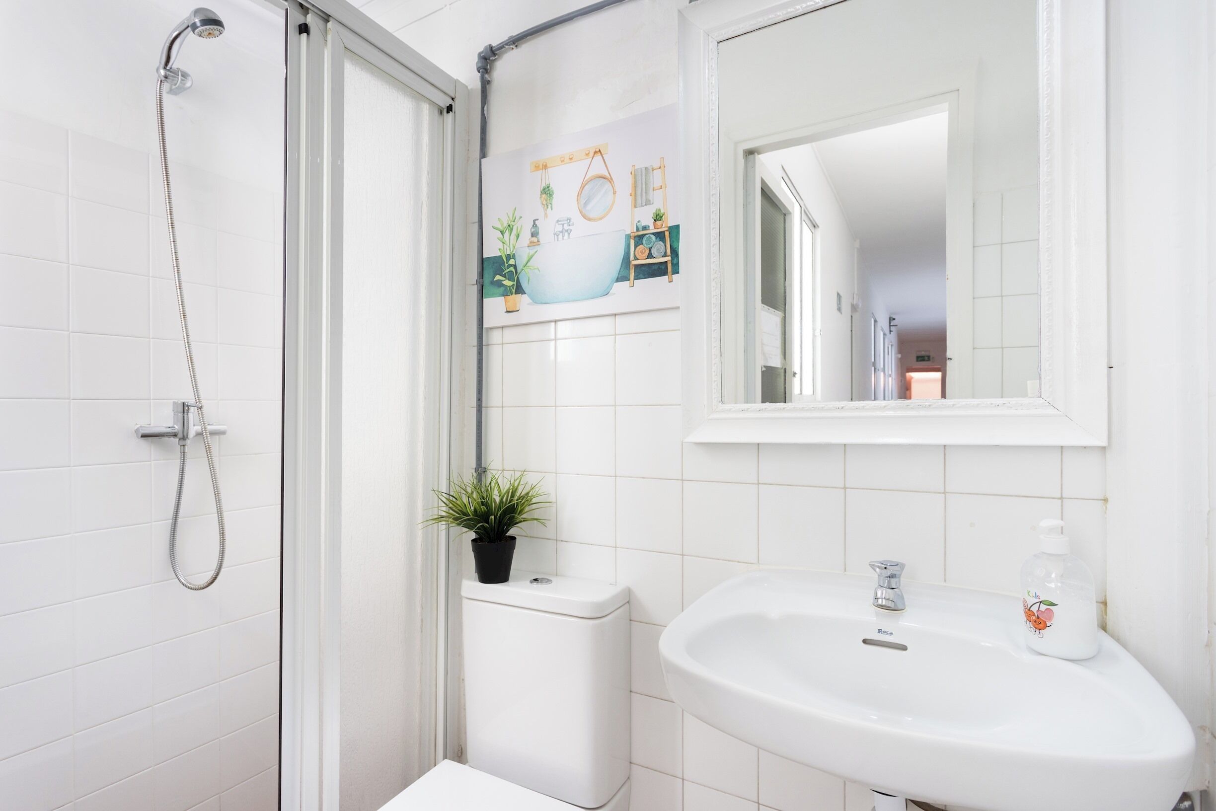 A bathroom with a shower, toilet, sink, and a mirror.